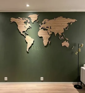 A Zebrano wooden world map installed on a green wall - front view