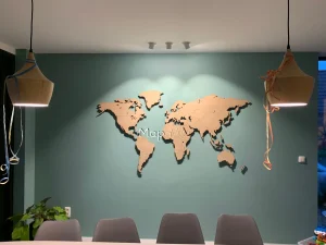 The magnetic Oak wooden world map made installed on a green wall.